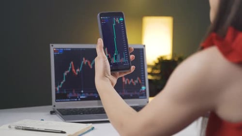 Woman Analyzes Stock Data on Phone and Laptop