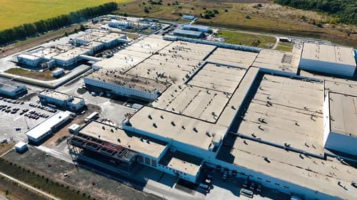 Footage above the roof of a large industrial plant. Numerous pipes are on the top of the factory.