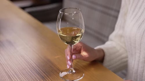 Wine Glass and Woman's Hand at Bar