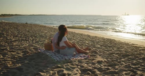 Man and Woman Sitting Together on a Sand in Front of the Sea Embracing