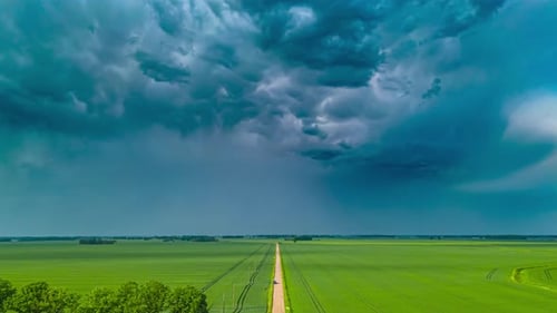 Dramatic Clouds over Green Field with Rural Road