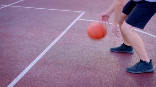 The Guy Basketball Player Dribbles the Ball Between the Legs in the Open Area