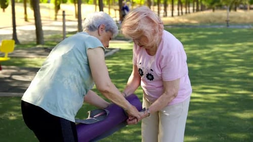 Senior Women Packing Yoga Mat Outdoors in Park