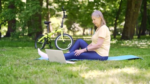 Senior Woman Uses Laptop in Park After Bike Ride