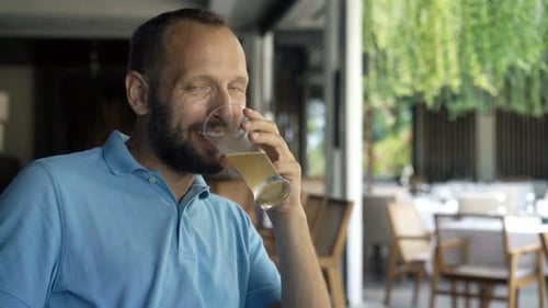 Happy Man Drinking Beer in Cafe at Night 30s