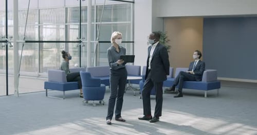 Business people in office meeting in lobby wearing protective face mask and using digital tablet