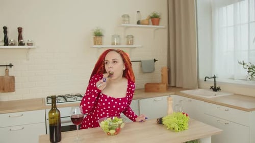 Woman With Red Hair Eats Salad in Kitchen