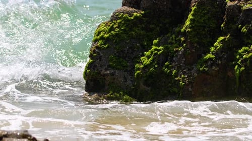 Waves Crashing Against Mossy Coastal Rock Formation