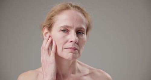 Mature Woman Touches Face in Studio Close Up