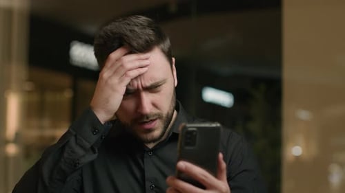 Man with Cell Phone Looking Concerned