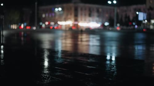 Nighttime City Reflections with Blurred Car Lights and Wet Pavement