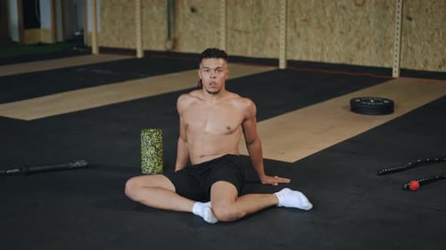 Man Stretching on Floor in Modern Gym