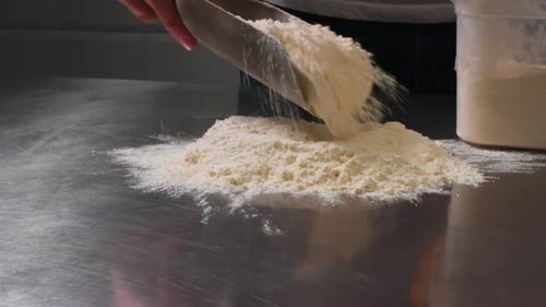 Sprinkling White Flour on Stainless Steel Table