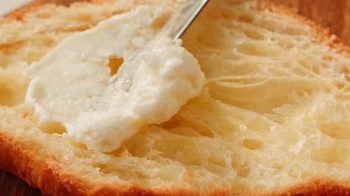 Cream Cheese Being Spread on a Slice of Bread