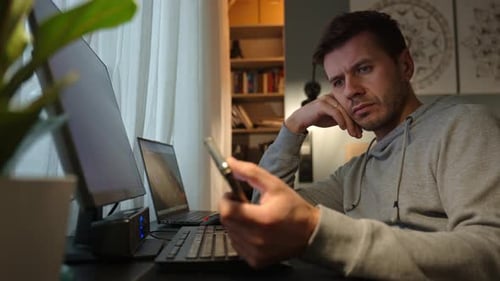 Freelancer Procrastinating at Home Office Scrolling Phone Instead of Working