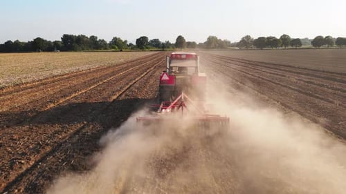 Tractor Working in Agricultural Field Cultivating and Plowing Dry Soil