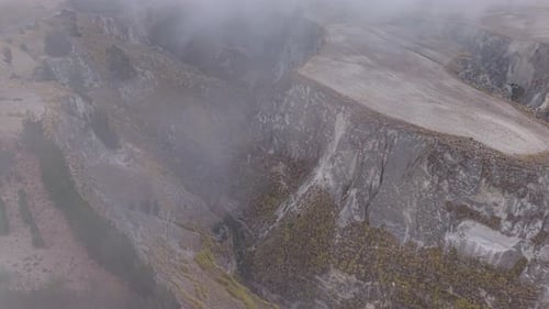 Aerial View of Low Hanging Clouds Drifting Across Deep Canyon Landscapes Revealing Rugged Andean