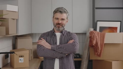 Man with Boxes Smiles Confidently in New Home