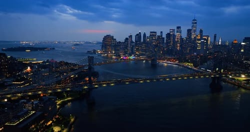 Beautiful New York bridges at night. Multiple cars move by the bridges with headlights on.