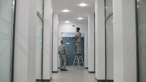 Men Working on Security Camera in Office Hallway