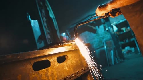 Man Welding Metal with Blowtorch in Workshop