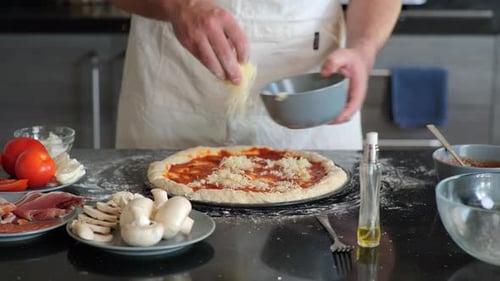A pizza chef adding fresh mozzarella cheese to pizza dough while making a traditional pizza pie.