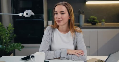 Portrait confiant d'une belle jeune fille des années 20 regardant la caméra assise à table au bureau à domicile