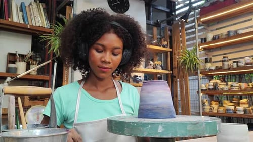 Females potter owners wearing apron sitting and painting a cup ceramics in pottery studio.