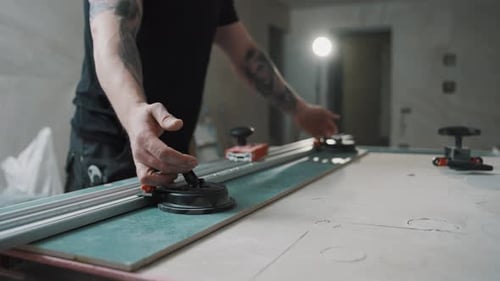 Man Using Tile Cutter in Unfinished Room