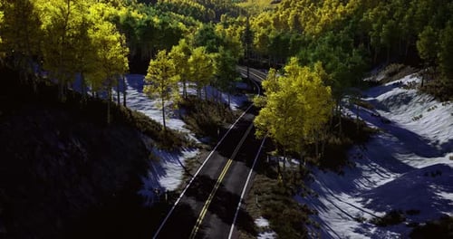 Majestic Winding Road Through Lush Green Hills with Patches of Snow