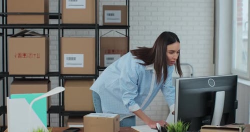 Woman scans package with smartphone in shipping office