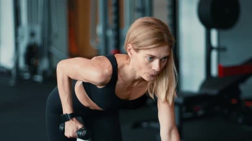 Woman Exercising With Dumbbell in Gym Focusing on Strength Training During Workout Session
