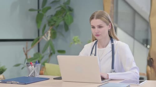 Young Woman Doctor Working at Laptop in Office