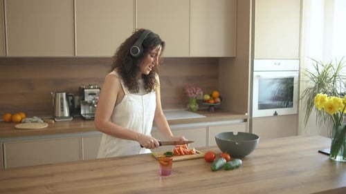 Happy Woman Prepares Salad While Listening to Music