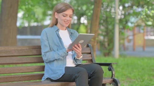 Woman Using Tablet on Park Bench During Daytime
