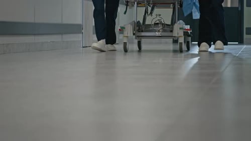Medical Staff Moving Gurney Through Hospital Corridor