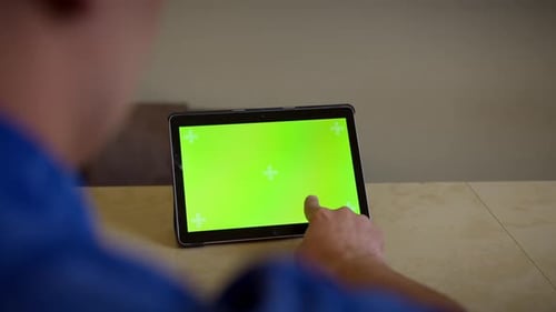 Man uses a tablet with a green screen presses his finger on the screen touches the screen