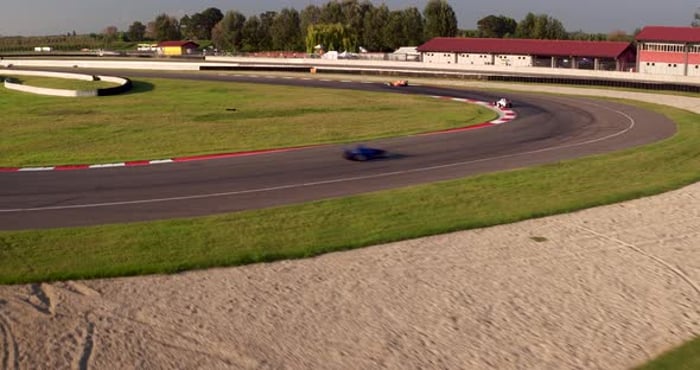 Aerial view over formula 1 racing track with cars speeding at high pace ...
