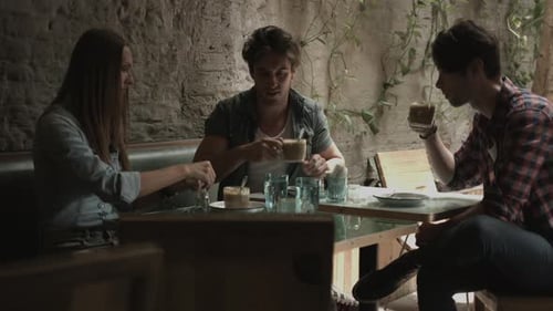 Friends having coffee and talking while sitting in coffee bar