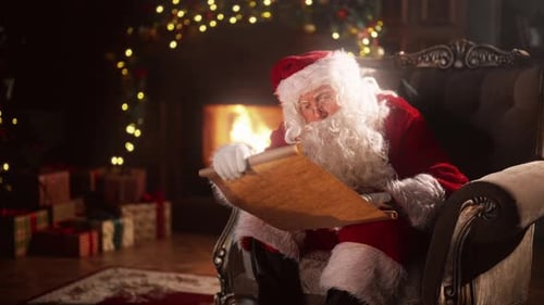 Santa Claus Reading Scroll by Fireplace at Christmas