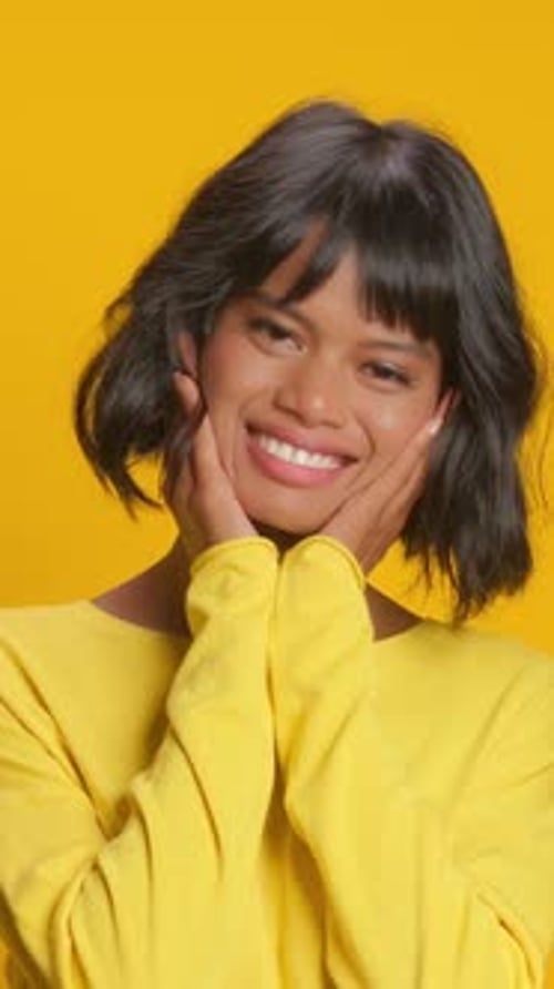 Woman Smiles With Hands on Face in Studio