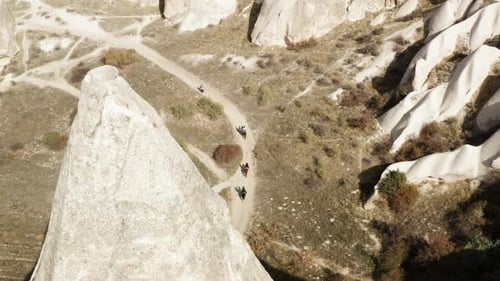 Tourists Exploring Scenic Landscape Of Cappadocia In Turkey While Riding In Horses - aerial shot