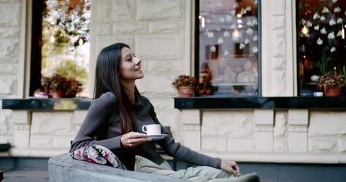 Young Woman Enjoying Coffee on Street