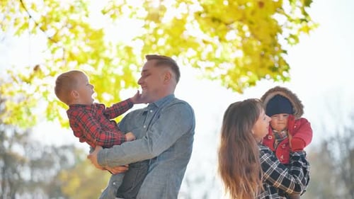 A Young Funny Family with Kids in the Park in the Fall
