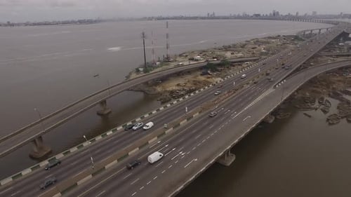 Drone View of Busy City Highway Bridge Crossing Water and Connecting Land