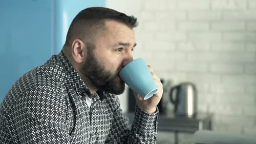 Man drinks coffee at a modern kitchen counter