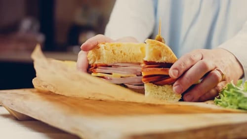 Cutting a Sandwich in Half on Wooden Board
