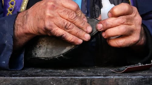Craftsman Repairing a Black Shoe with Glue