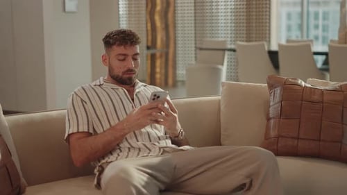 Man Relaxing on Couch with Mobile Phone