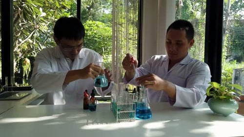 Researcher blending the reagent or chemical liquid into beaker. Laboratory science, research.
